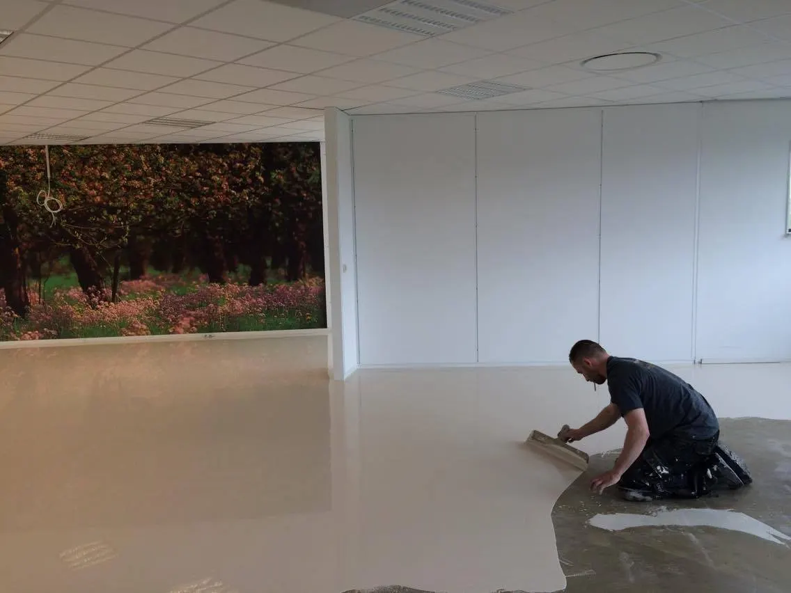 Vakman egaliseert de vloer van een kantoorruimte